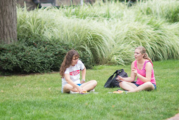 Photo of two students sitting on the lawn talking. Link to Gifts by Will.